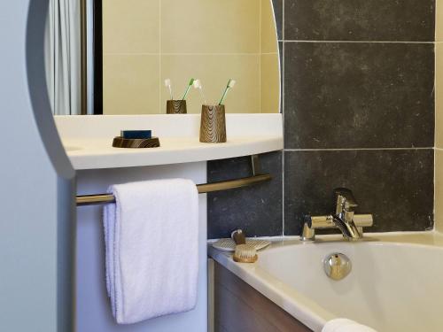 a bathroom with a sink and a tub and a mirror at Aparthotel Adagio Bordeaux Centre Gambetta in Bordeaux