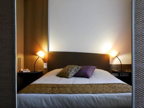 a room with a bed with two lamps and two pillows at Aparthotel Adagio Bordeaux Centre Gambetta in Bordeaux