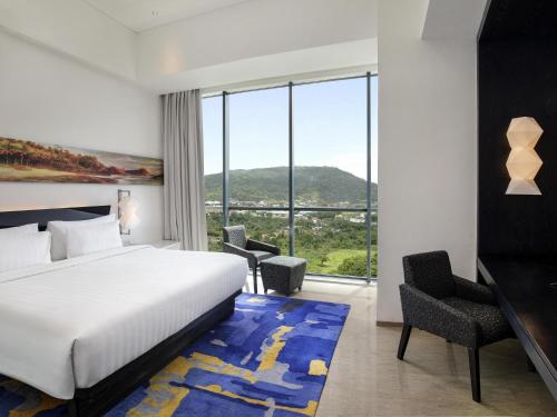 a hotel room with a bed and a large window at Novotel Lampung in Bandar Lampung