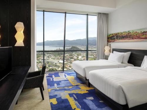 a hotel room with two beds and a large window at Novotel Lampung in Bandar Lampung