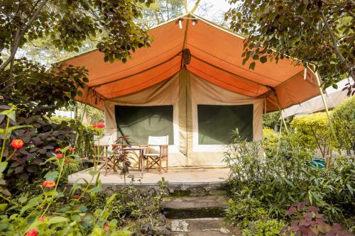 a tent with a table and chairs in a garden at Kikopey Beach Camp Lake Elementaita in Gilgil