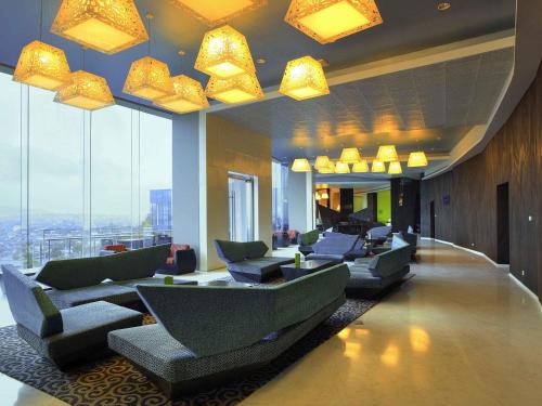 a hotel lobby with couches and chairs and windows at Novotel Lampung in Bandar Lampung