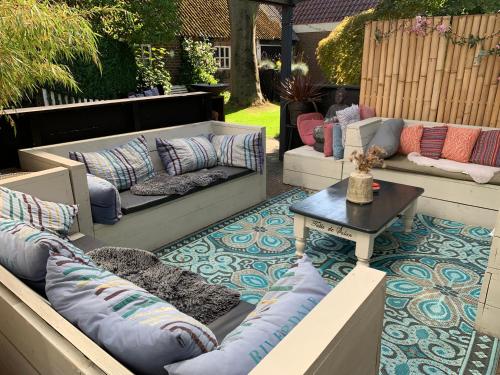 a patio with two couches and a table on a floor at Gezellige Ruime Villa incl Hottub Sauna en Gamesroom in Den Ham