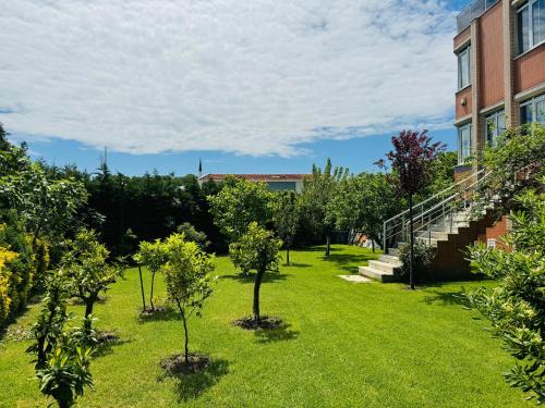 a garden with trees in the grass next to a building at Treekos Suite Hotel Istanbul Airport in Arnavutköy