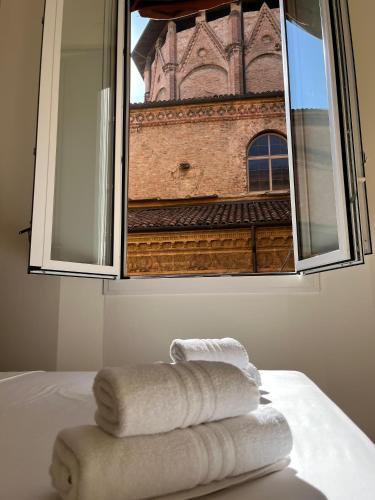 a window with towels on a bed with a building at Zambo Residence in Bologna