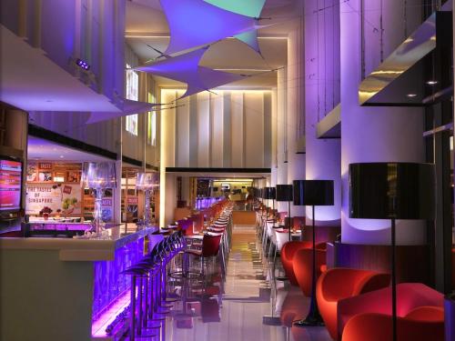 a bar with red chairs and purple lighting in a restaurant at Ibis Singapore on Bencoolen - Newly Renovated in Singapore