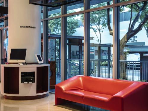 a red couch in a lobby with a computer on a desk at Ibis Singapore on Bencoolen - Newly Renovated in Singapore
