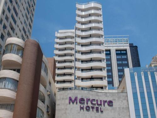 ein Hotelschild vor zwei hohen Gebäuden in der Unterkunft Mercure Camboriu in Balneário Camboriú