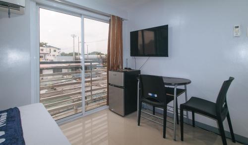 a room with a table and a television and a window at V-Cloud Hills Boarding House Near NAIA Terminal in Manila