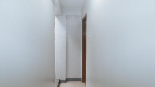 a hallway with white walls and a wooden door at V-Cloud Hills Boarding House Near NAIA Terminal in Manila