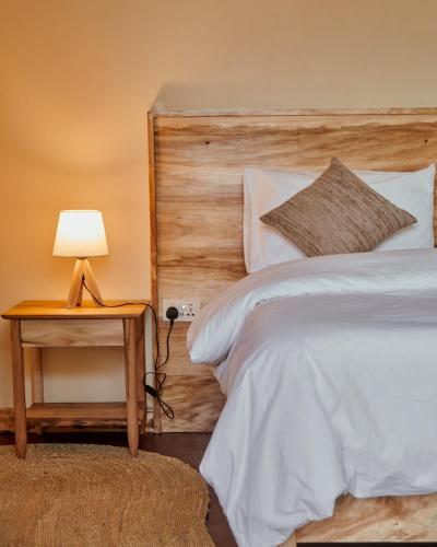 a bedroom with a bed and a table with a lamp at Samora River Lodge in Arusha
