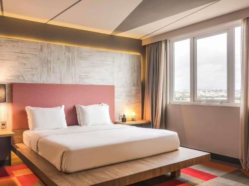 a bedroom with a large bed and a large window at Novotel Porto Alegre Airport in Porto Alegre