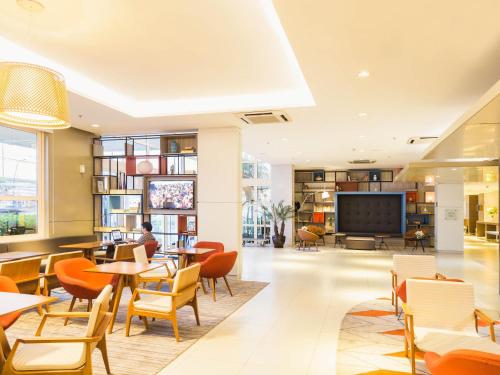 a restaurant with tables and chairs and a tv at Novotel Porto Alegre Airport in Porto Alegre