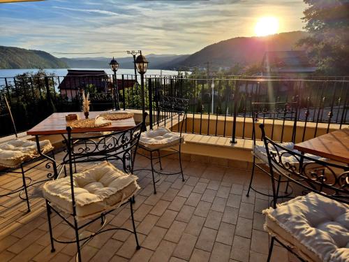 a patio with tables and chairs and a view of the water at Pensiunea Casa Mircea & Restaurant in Eşelniţa