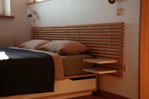 a bedroom with a bed with a wooden headboard at Mokaito Namai in Sadžiūnai