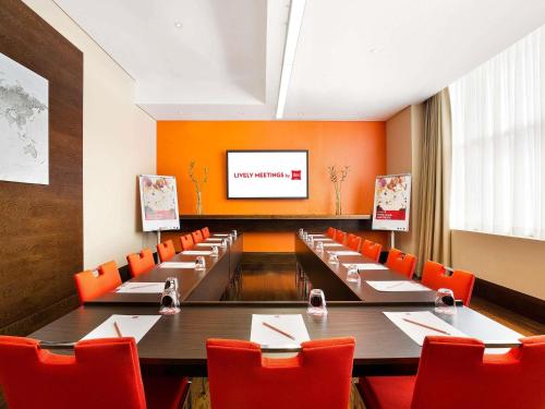 a conference room with a long table and red chairs at ibis Dubai Al Rigga in Dubai