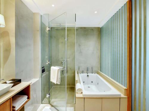 a bathroom with a tub and a glass shower at Novotel Hyderabad Airport in Hyderabad