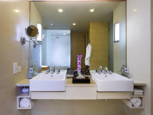 a bathroom with two sinks and a large mirror at Novotel Hyderabad Airport in Hyderabad