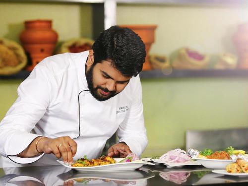 a chef preparing a plate of food in a kitchen at Novotel Hyderabad Airport in Hyderabad