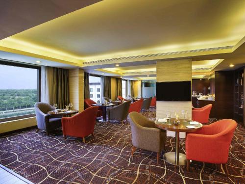 a restaurant with tables and chairs and a large window at Novotel Hyderabad Airport in Hyderabad