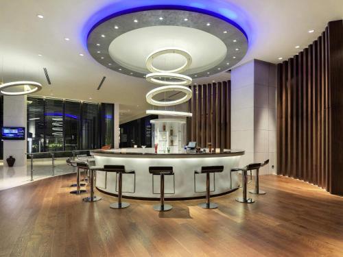 a lobby with a bar with stools and a circular ceiling at Novotel Hyderabad Airport in Hyderabad