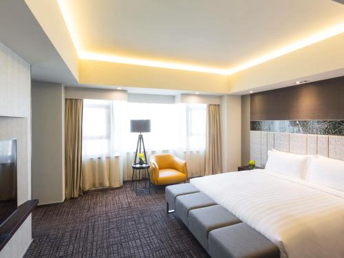 a hotel room with a large bed and a yellow chair at Grand Mercure Shanghai Hongqiao in Shanghai