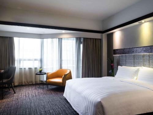 a hotel room with a large bed and a chair at Grand Mercure Shanghai Hongqiao in Shanghai