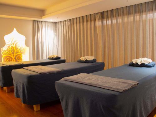 two beds sitting in a room with curtains at Grand Mercure Shanghai Hongqiao in Shanghai
