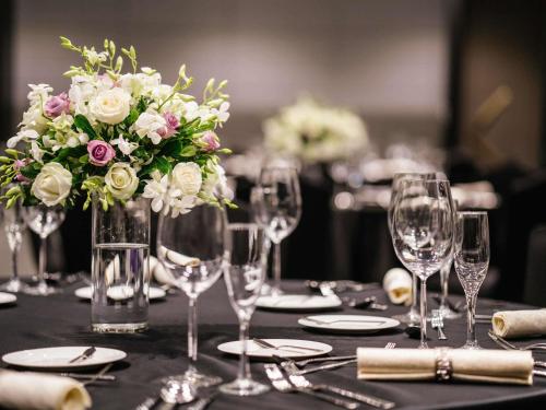 a table with wine glasses and a vase of flowers at Grand Mercure Shanghai Hongqiao in Shanghai