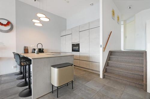 a kitchen with a counter and a bar with stools at Kabbelaarsbank 504 - Port Marina Zélande in Ouddorp
