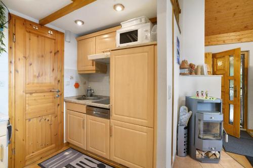 a kitchen with wooden cabinets and a microwave at Ferienhaus am Wald mit Südblick in Steina