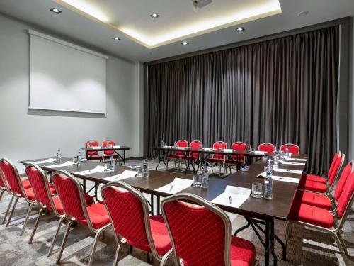 a conference room with tables and red chairs and a screen at Novotel Trabzon in Trabzon