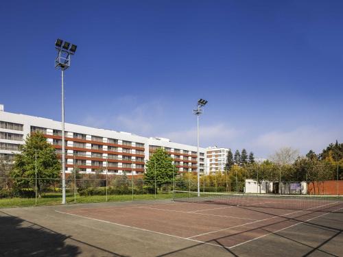 a tennis court in front of a large building at Novotel Trabzon in Trabzon