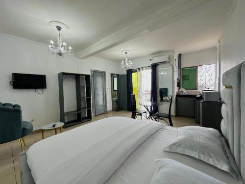ein Schlafzimmer mit einem großen weißen Bett und ein Wohnzimmer in der Unterkunft Loft Residence KOTTO in Douala