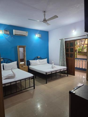 two beds in a room with a blue wall at Oceanic Beach Guest House in Calangute