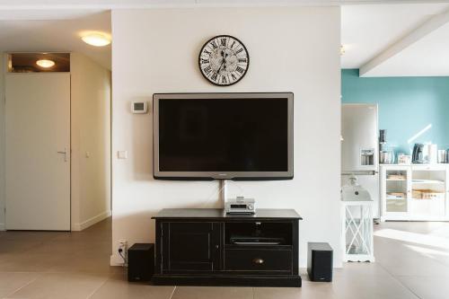 a flat screen tv on a wall with a clock at Kabbelaarsbank 512 - Port Marina Zélande in Ouddorp