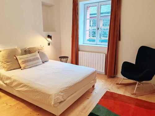 a bedroom with a bed and a chair and a window at Maison chic du Jerzual in Dinan