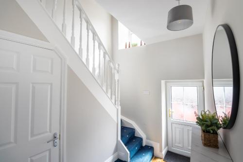 a hallway with a staircase with a mirror and a door at The Mariner, Westport in Westport