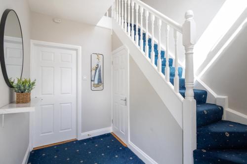 a hallway with blue carpet and stairs with a mirror at The Mariner, Westport in Westport