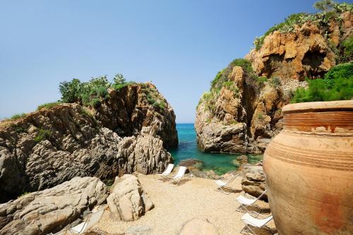 a beach with chairs and a large vase at Le Calette Bay in Cefalù