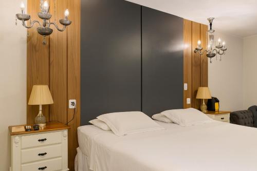 a bedroom with a large white bed and two lamps at Eleganz Suítes Exclusive Centro in Gramado