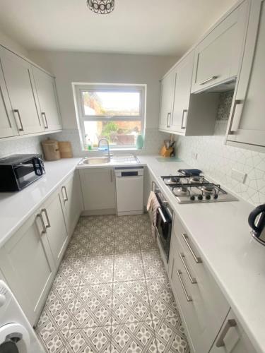 a white kitchen with a sink and a stove at City Centre 4 Bedroom House in Winchester