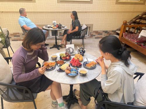 een vrouw en een meisje aan een tafel met eten bij Nigina INN in Bukhara