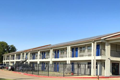 an apartment building with blue windows and a fence at Deluxe Inn Motel By OYO Grand Prairie Interstate 30 in Grand Prairie
