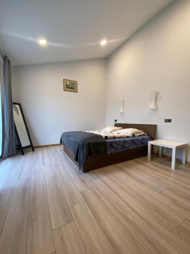 a bedroom with a bed and a table on a wooden floor at Family house in Valmiera