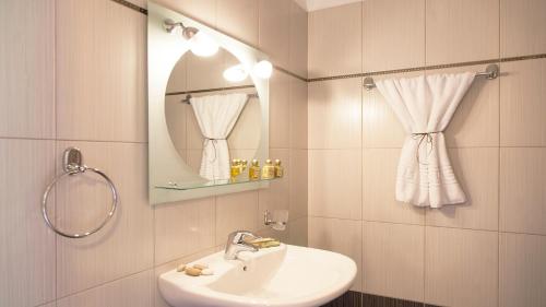 a white bathroom with a sink and a mirror at Christianna Studios in Nikiana