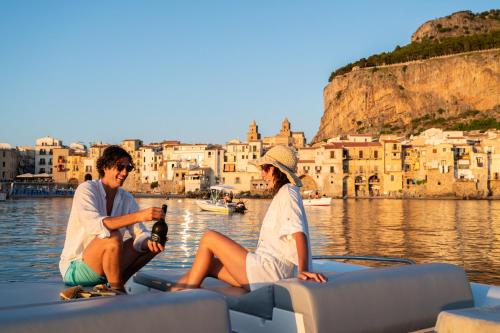 two people sitting on a boat in the water at Le Calette Bay in Cefalù