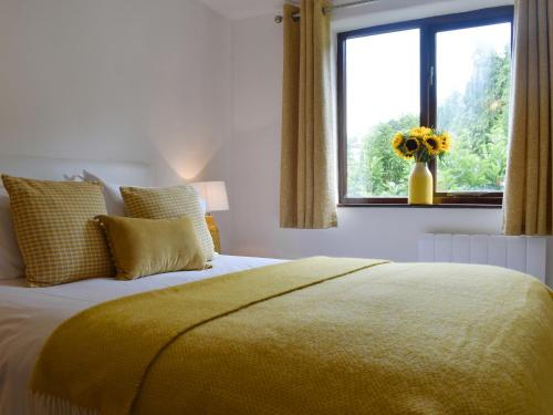a bedroom with a bed with a yellow blanket and a window at Brameley in Cheriton Bishop