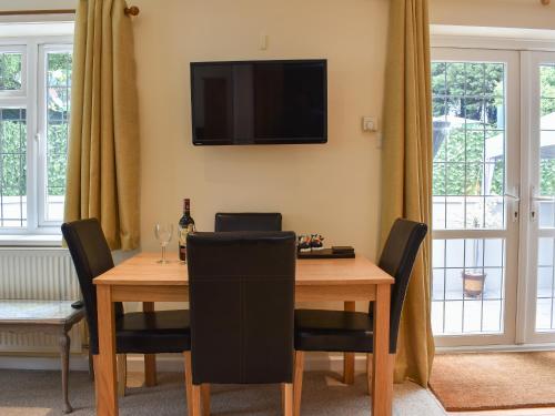 a dining room table with chairs and a television on the wall at Rose Corner in Countess Wear