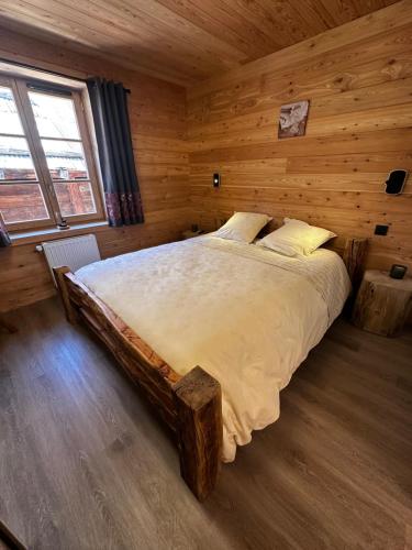 a bedroom with a large bed in a wooden room at Maison Cœur Clarée in Névache